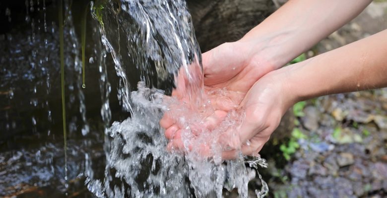 Drinking water and natural water in the hands.