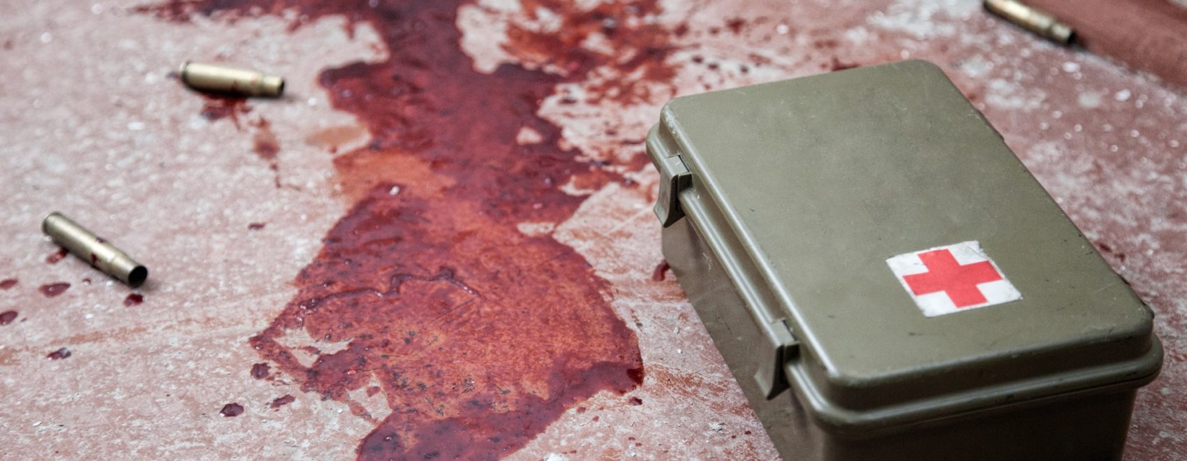 Military firs aid kit on floor with blood stains