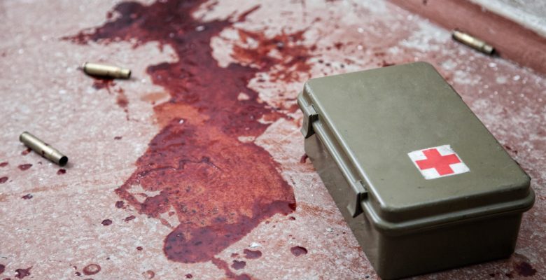 Military firs aid kit on floor with blood stains