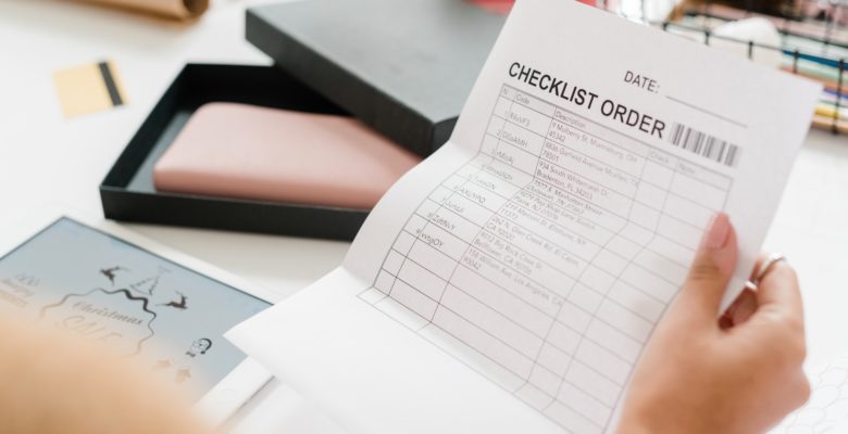 Paper with checklist order held by young female shopper looking through it