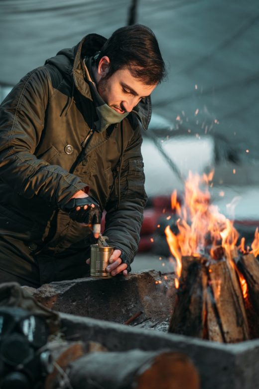 Financial Survival for Doomsday Preppers person cooking canned food on fire