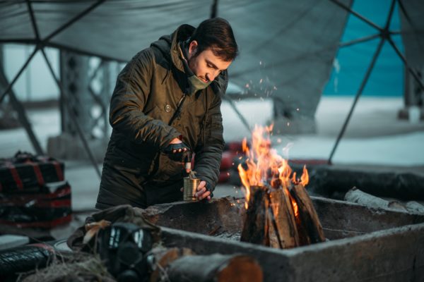 finanční přežití pro Doomsday Preppers osoba vaření konzervované jídlo v ohni